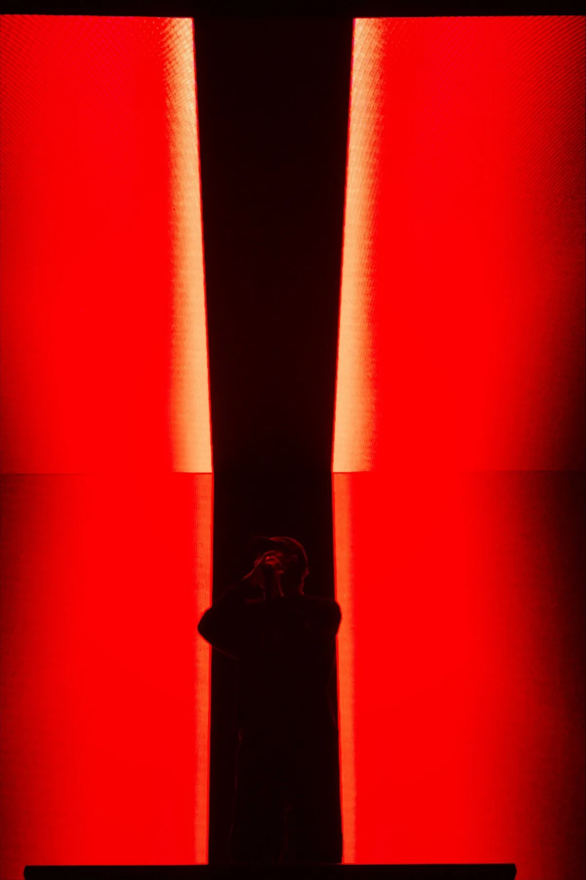 Silhouette in controluce nello spiraglio tra due pannelli LED rossi